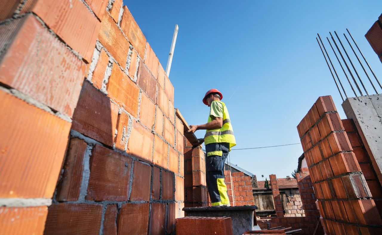 Pedreiro construindo um muro em um dia ensolarado