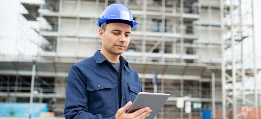Homem com capacete usando tablet em construção