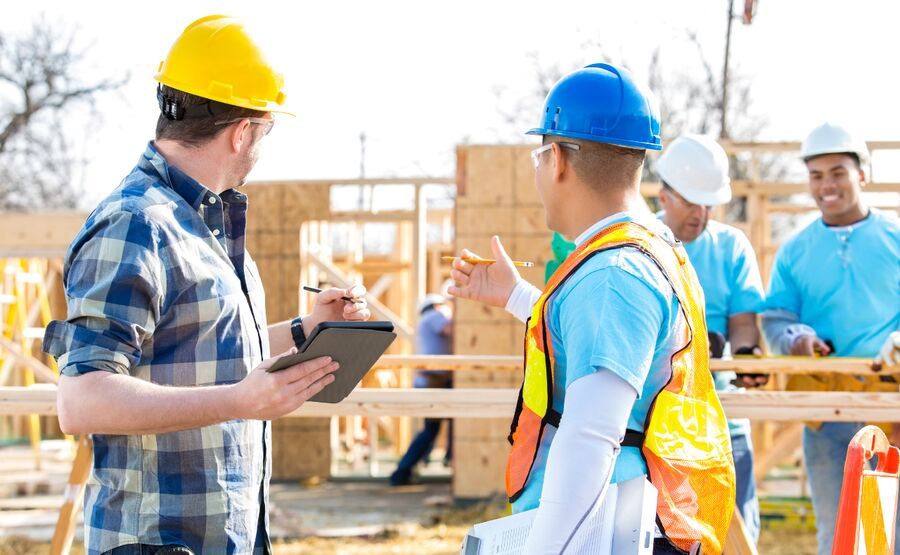 Dois homens em obra discutindo planejamento de construção.