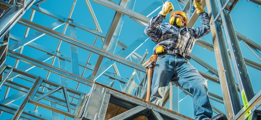 Trabalhador em construção com estrutura metálica.